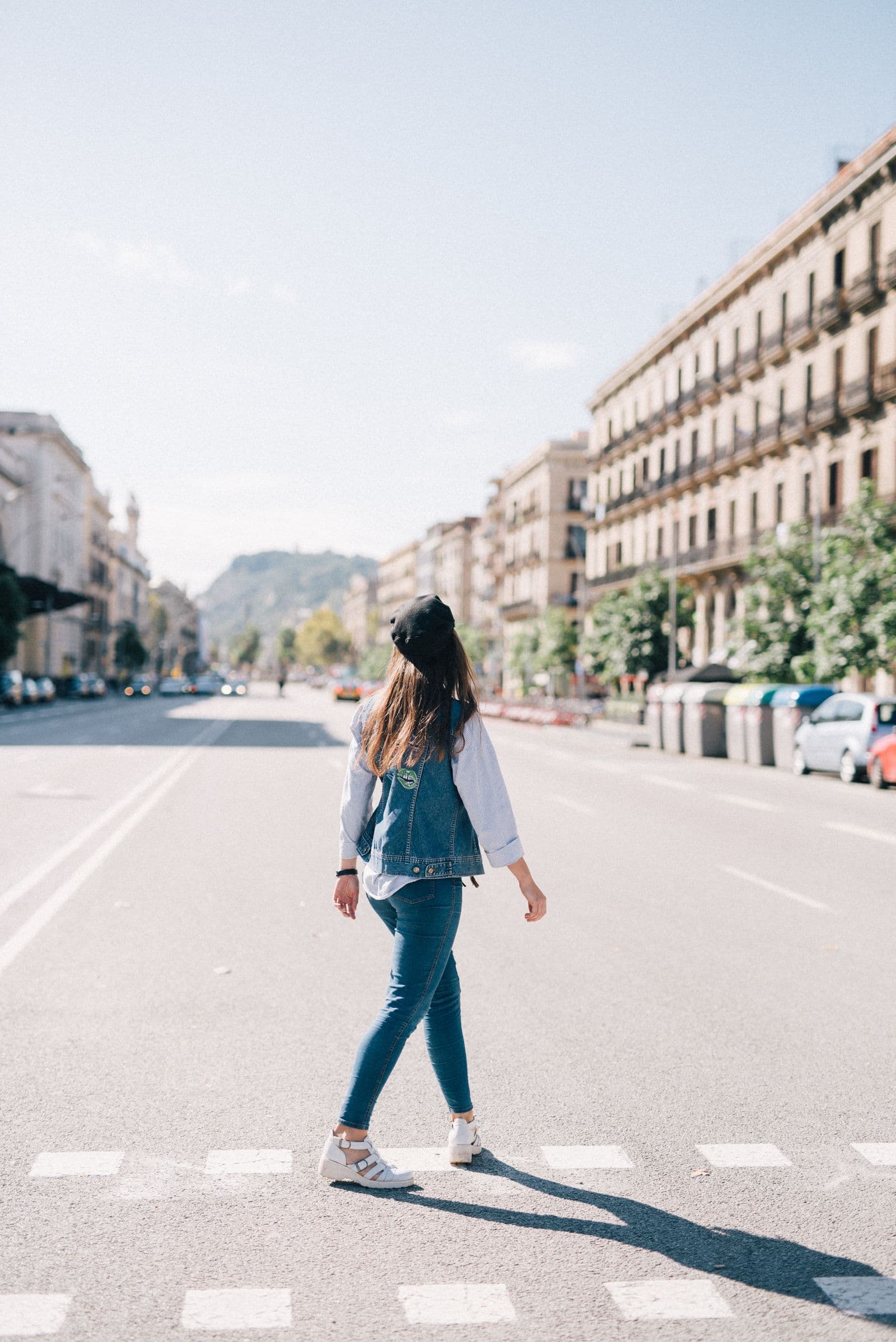 Woman crossing a sunny Barcelona street in denim