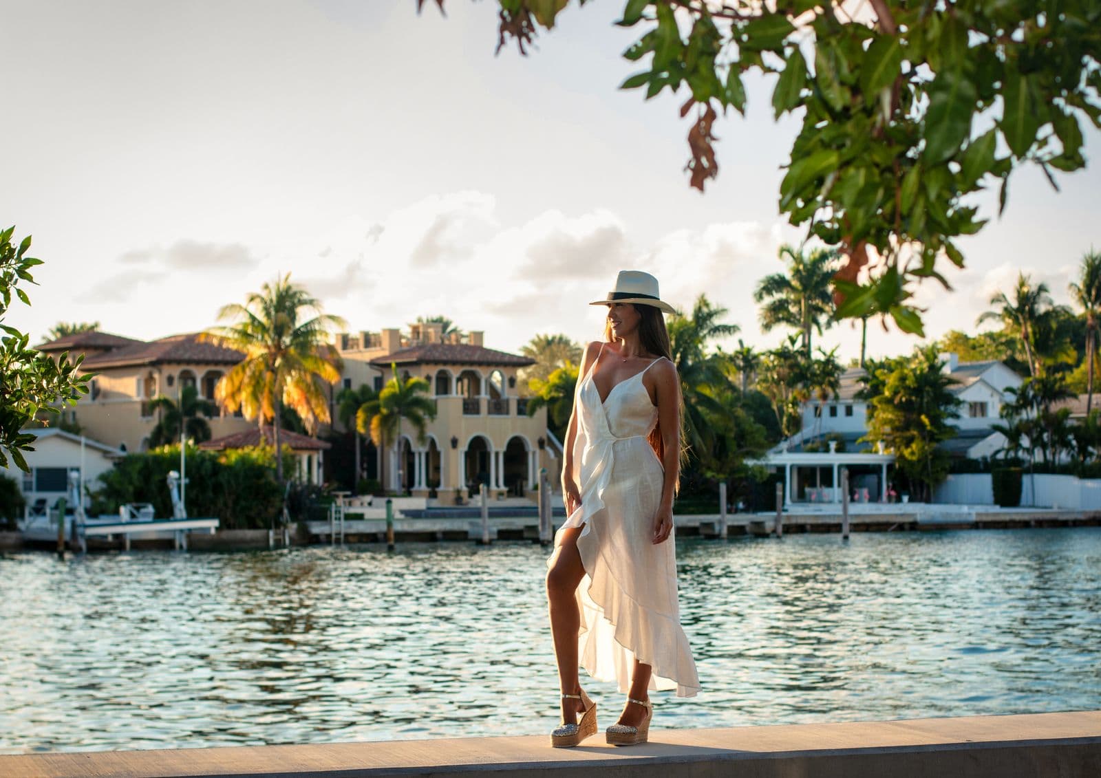 Woman in a white dress and sun hat near a Miami waterfront