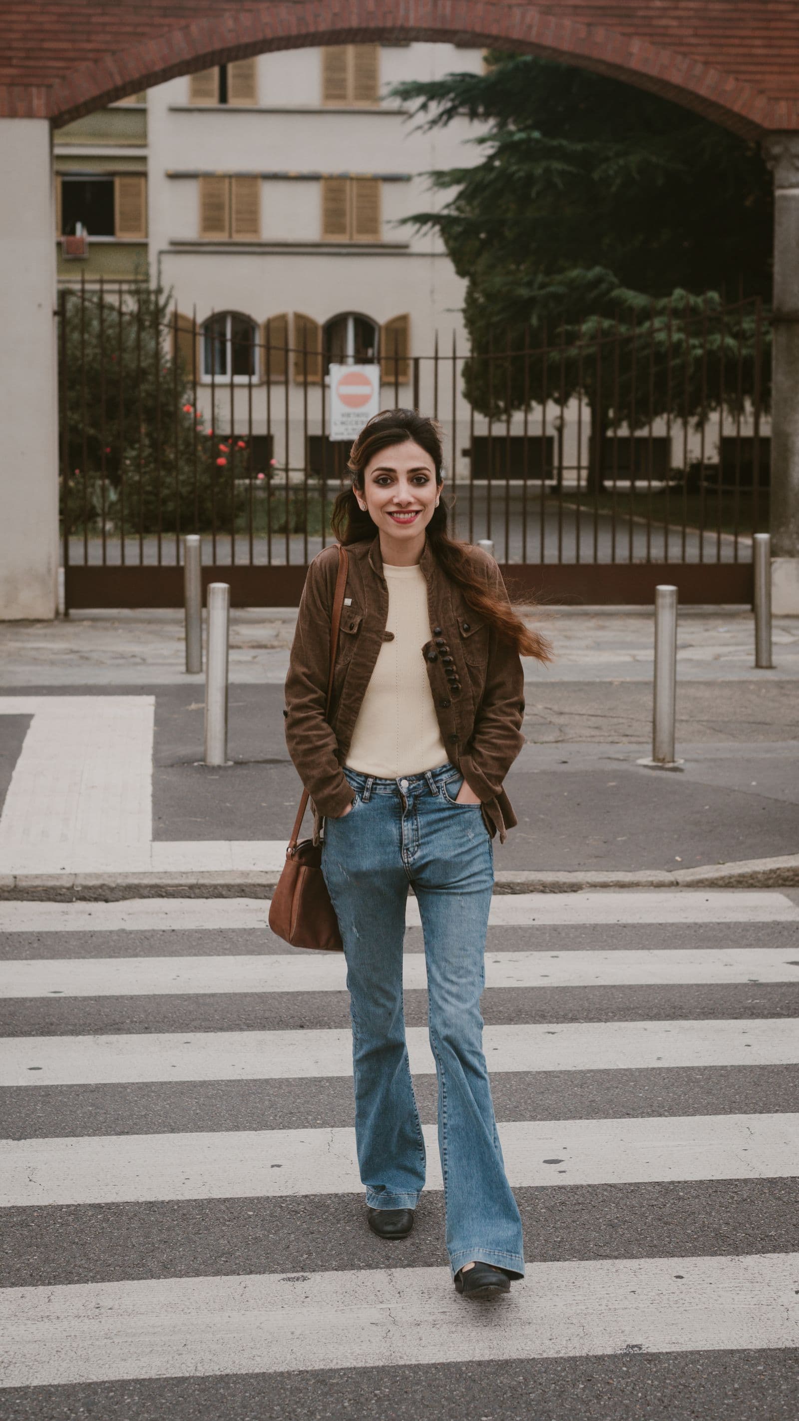 Woman in a light jacket crossing a city street