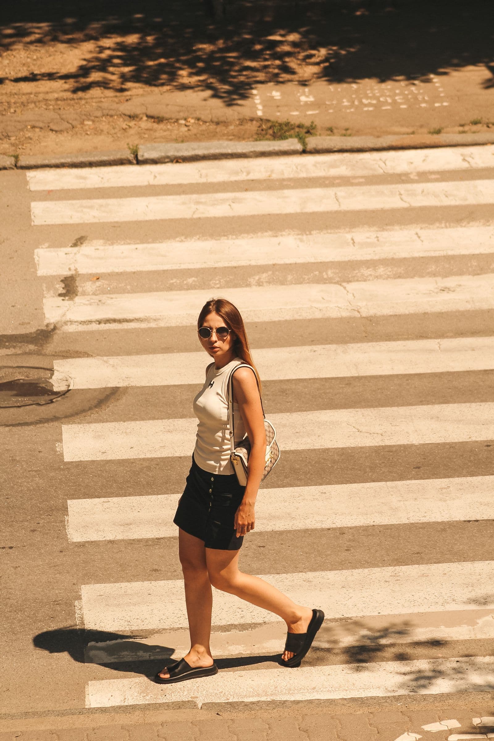 Woman wearing a light outfit at an urban crosswalk