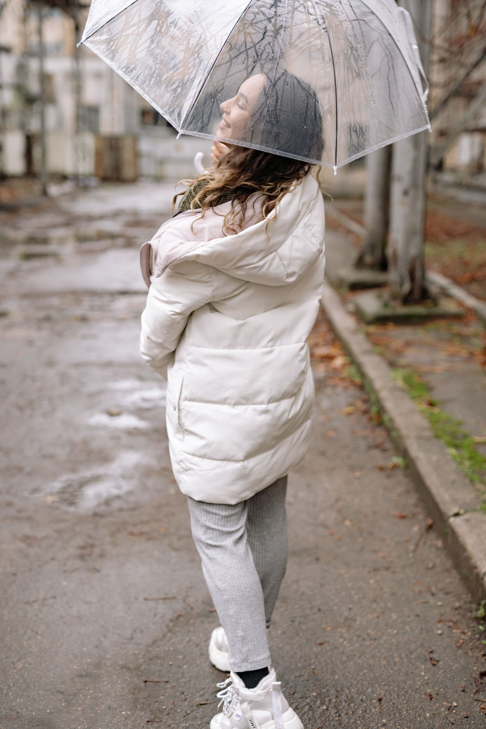 Woman in a white winter jacket holding an umbrella