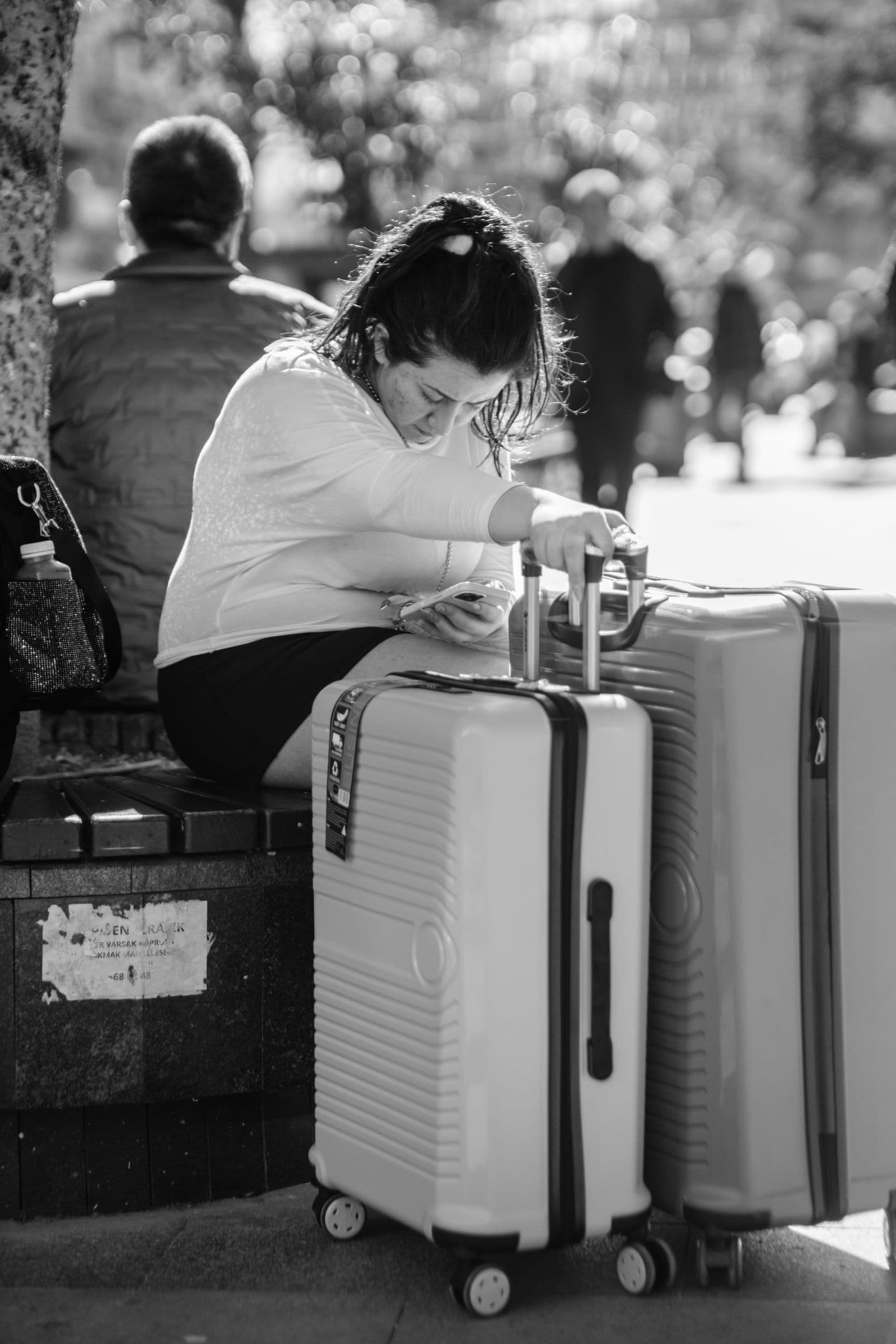 Woman traveling through a city square with rolling luggage