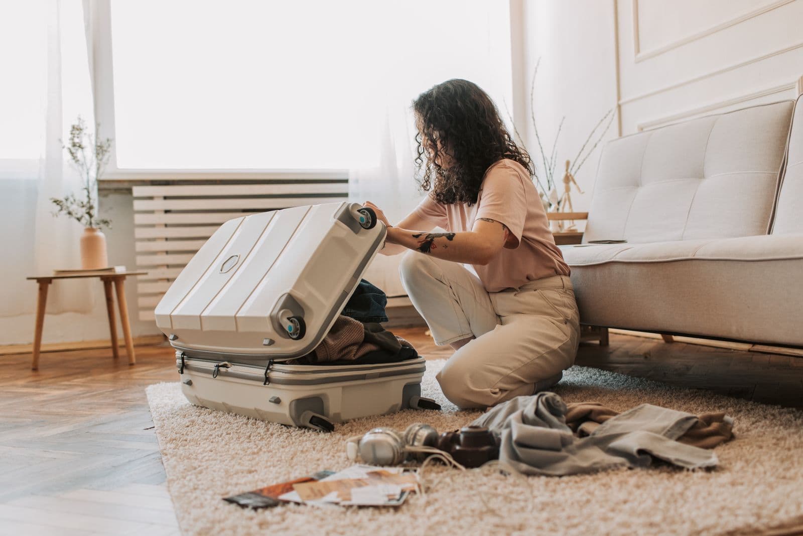 Woman packing a neutral travel wardrobe into a suitcase