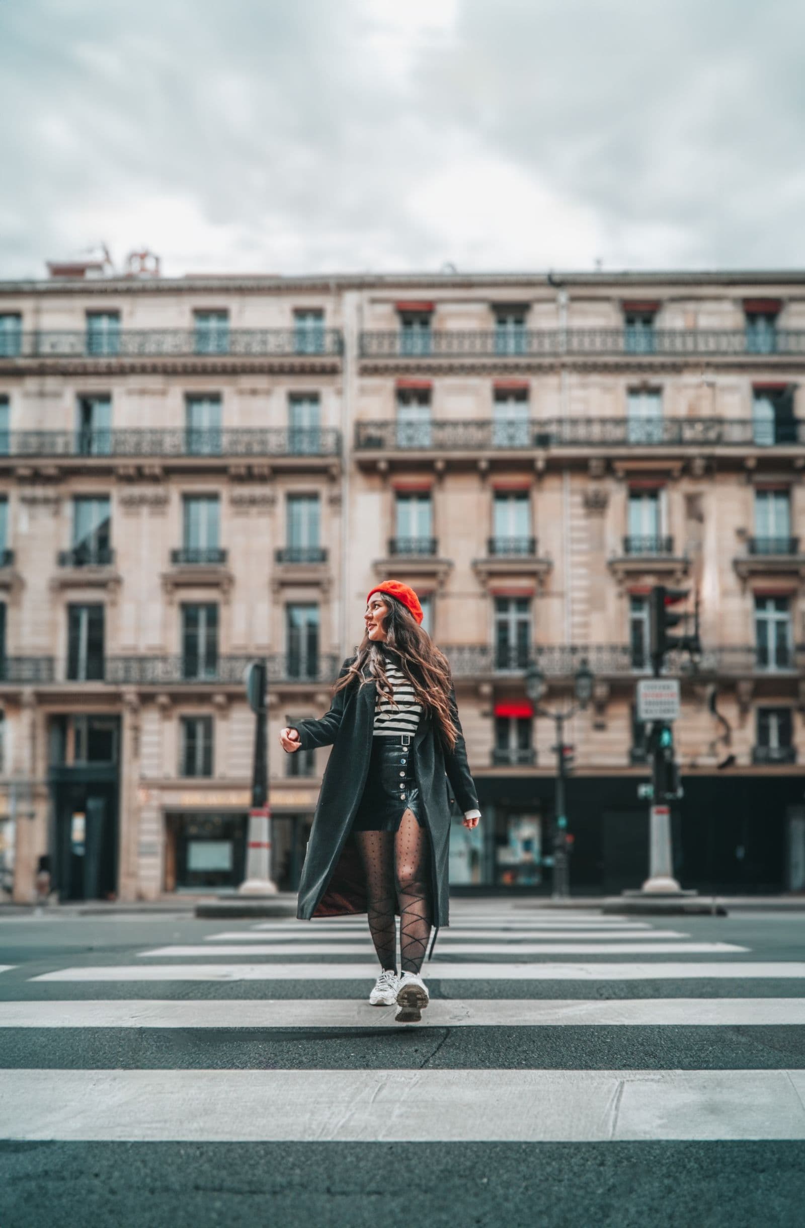 Woman in a dark coat and red beret crossing a Paris street
