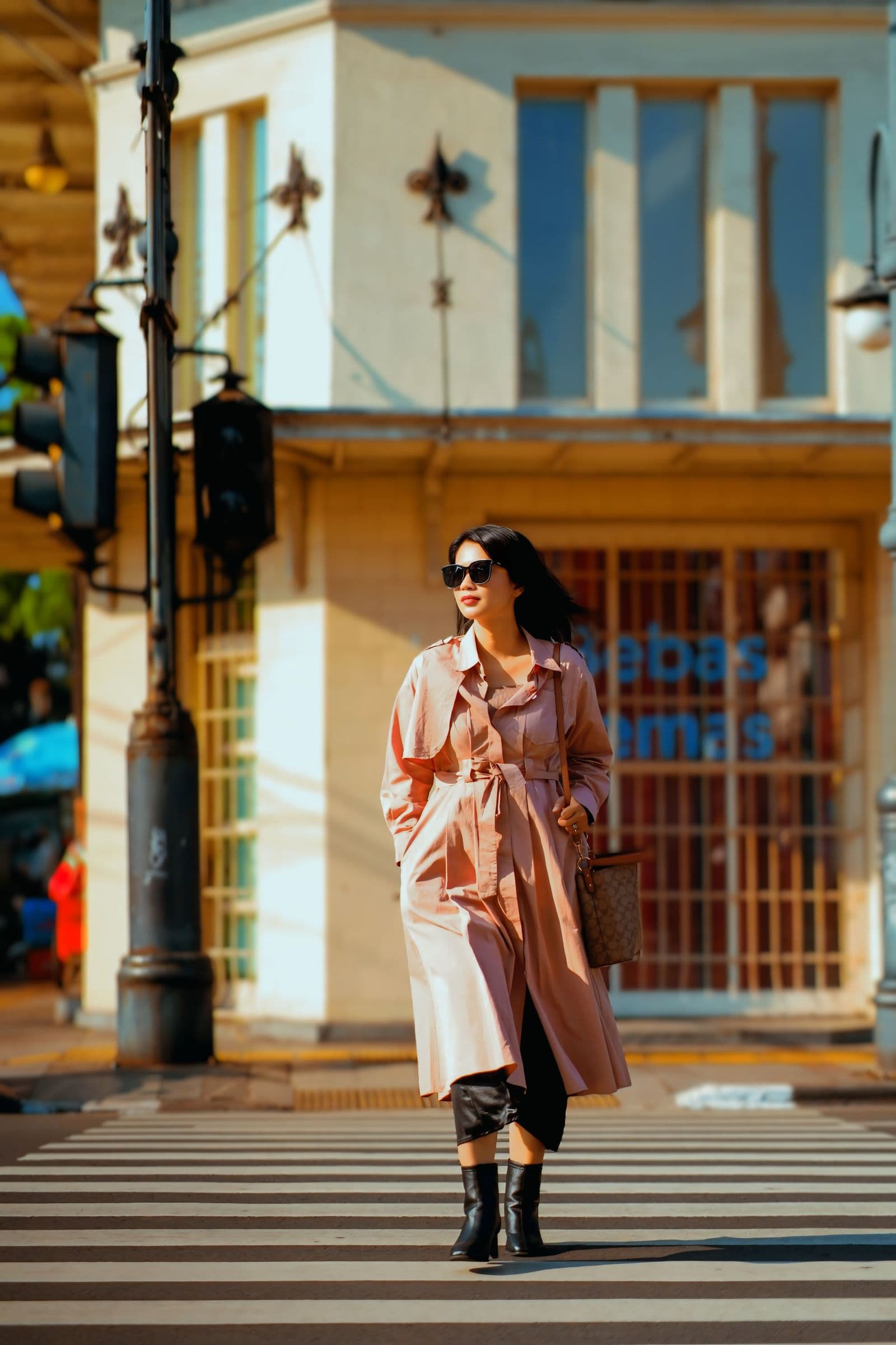 Stylish woman in a trench coat crossing a city street